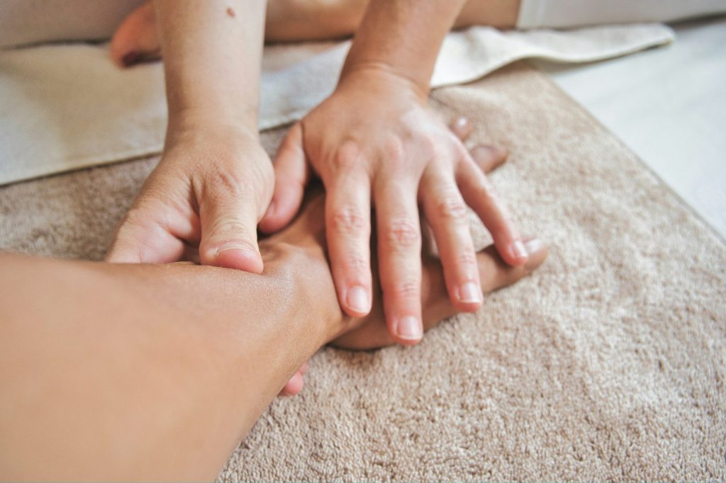 Close-up of a sports massage therapist's hands applying deep tissue manual therapy to a client's hand and wrist.